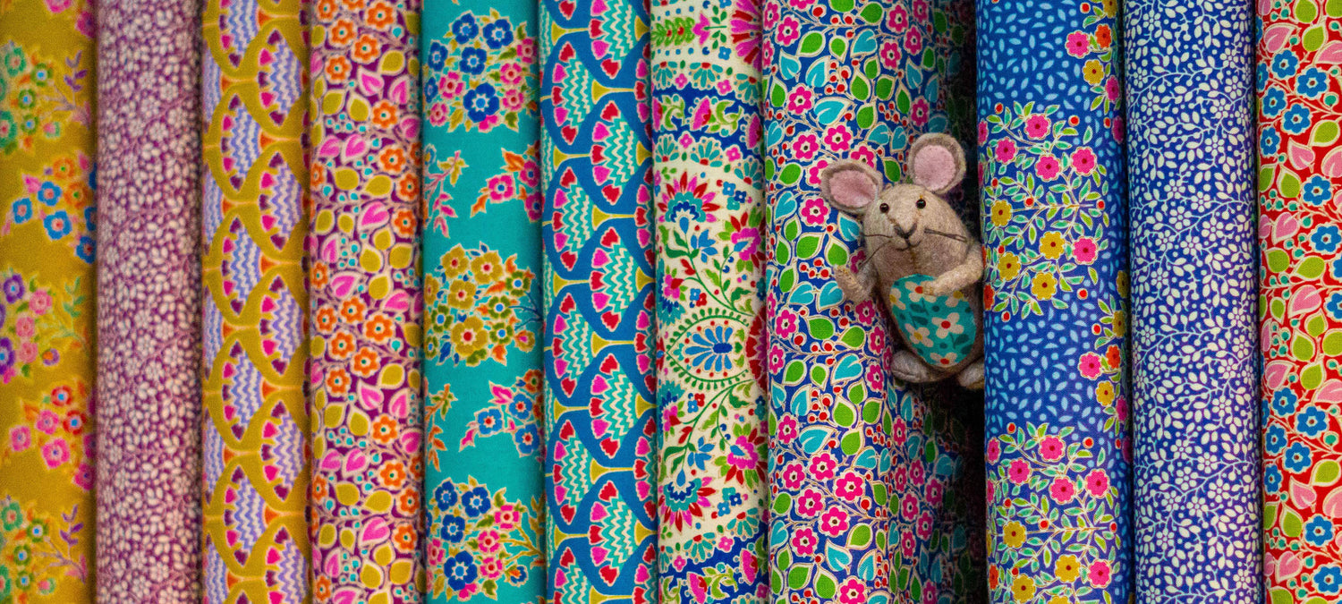 Picture of the shops mascot, Julius the mouse, peeping out from within some fabric.